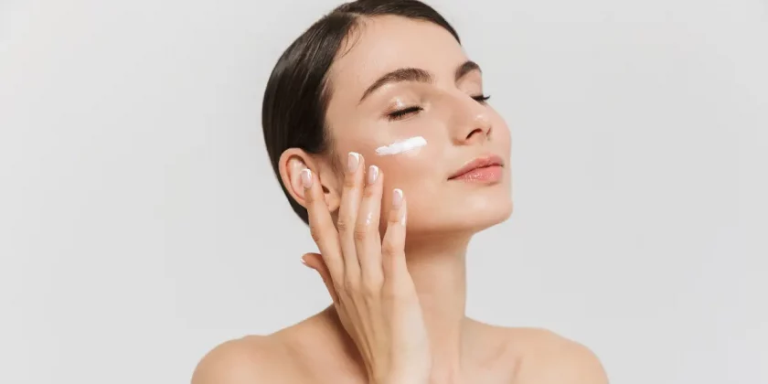A woman puts moisturizer on her face